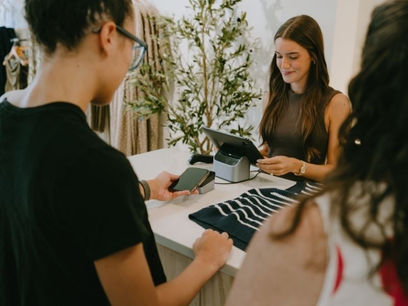 Young woman using mobile wallet at store